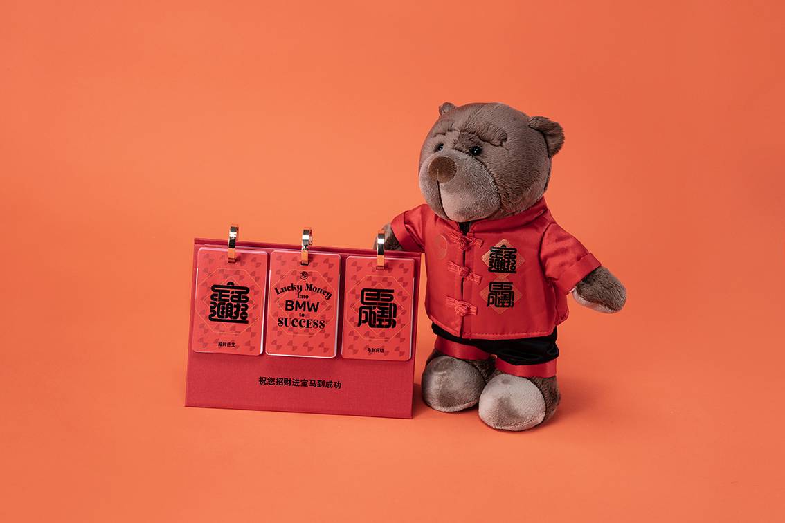 A stuffed bear holds a sign wishing Happy Chinese New Year and "BMW to success"