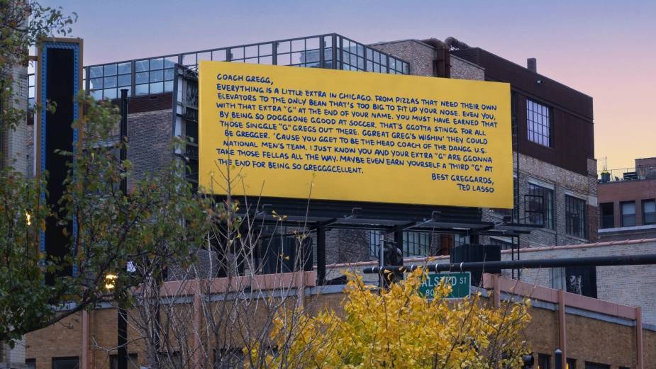 a yellow billboard on a building displays words of encouragement from Coach Ted Lasso