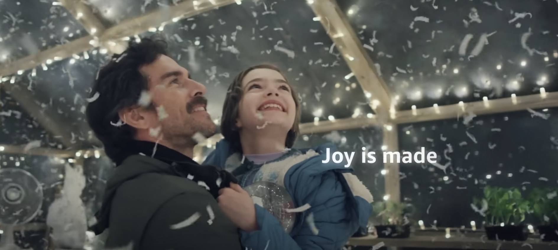 Screen-Shot-2023-06-16-at-1.12.12-PM Father and daughter standing in a greenhouse with fake paper snow all around them