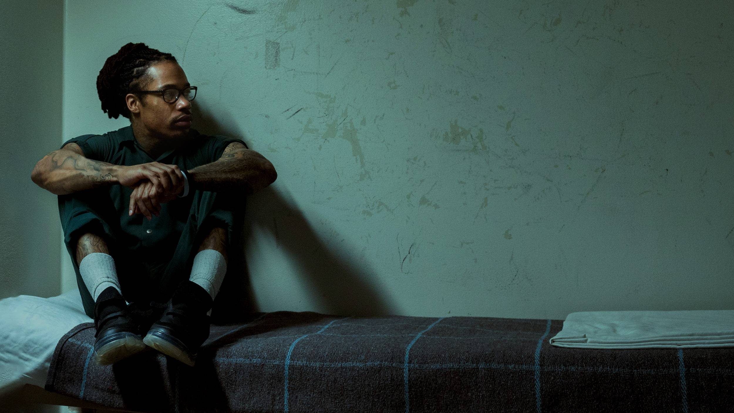 A man on the bed in his prison cell