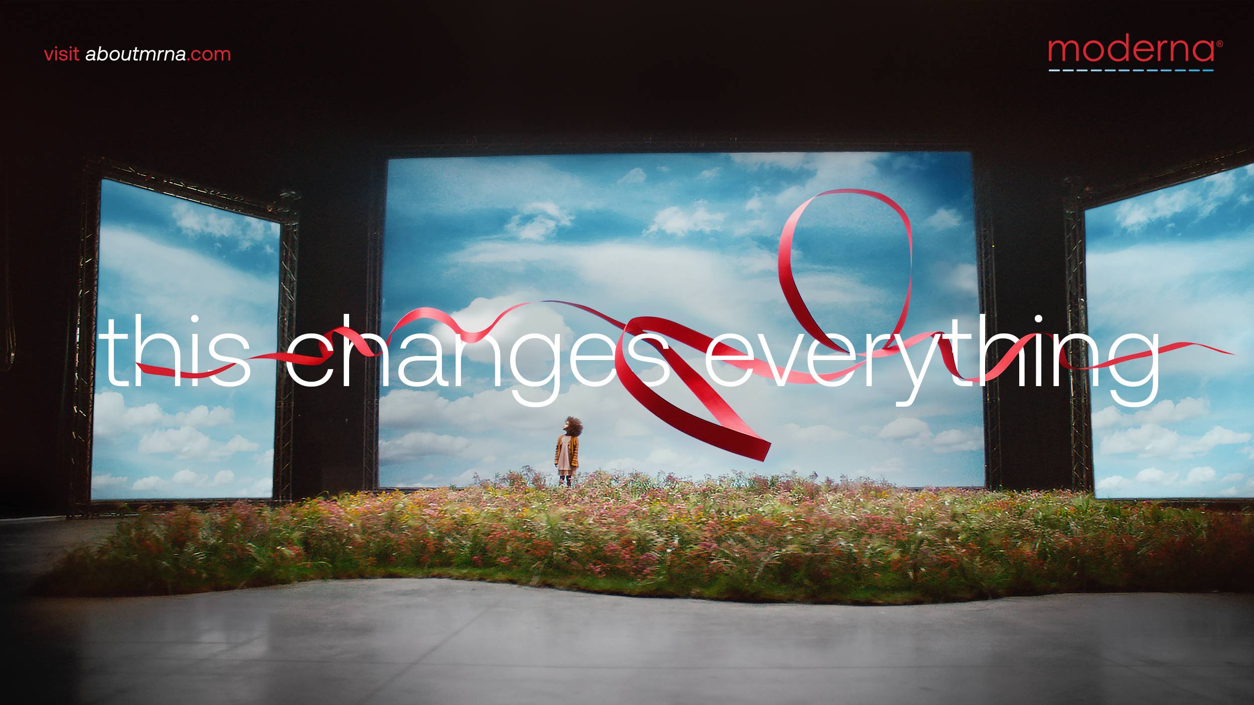 Moderna "this changes everything" visual of a red ribbon taking up the entire length of a meadow