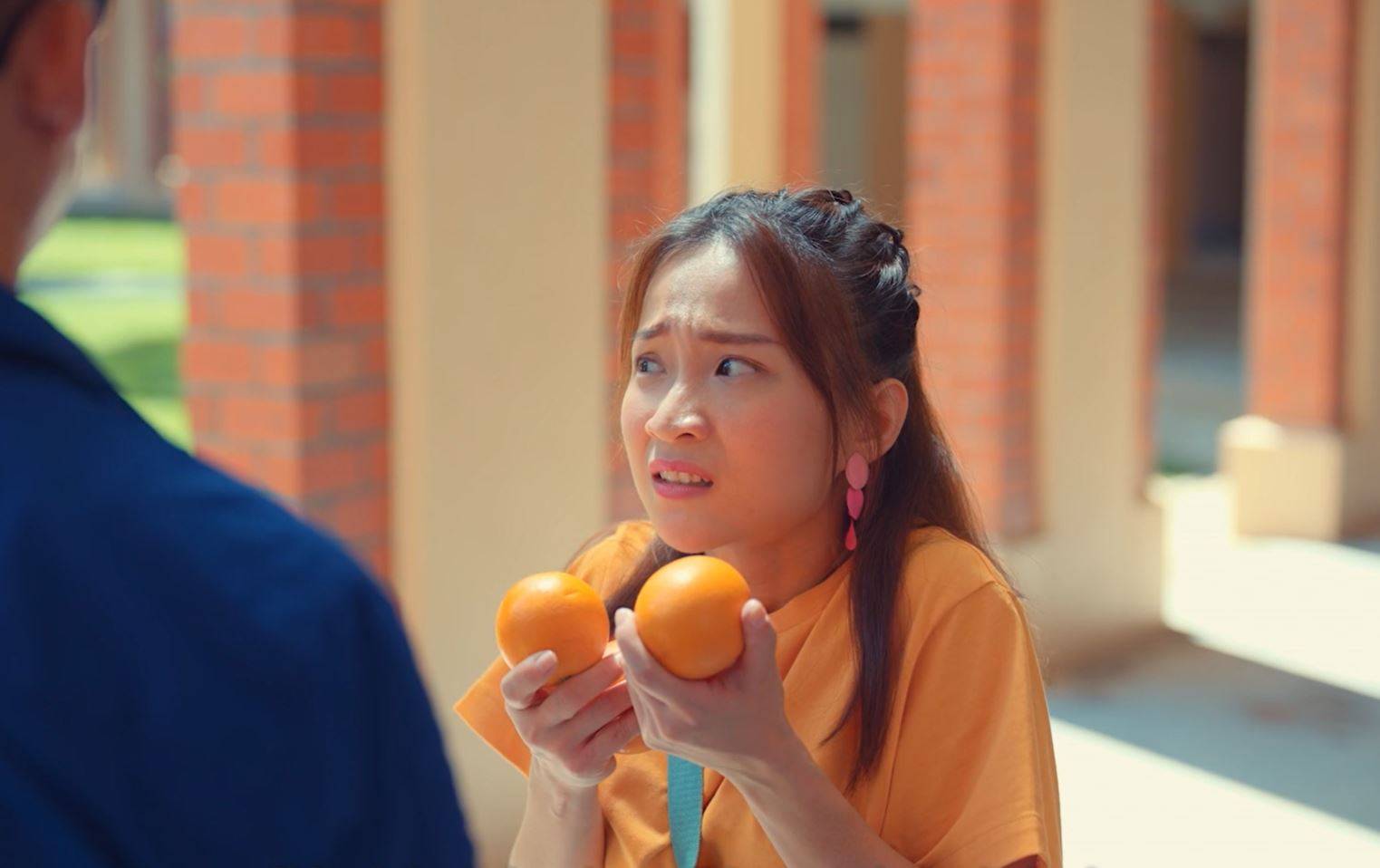 SG Enable UnAwkward: A girl awkwardly holds oranges, unsure what to say